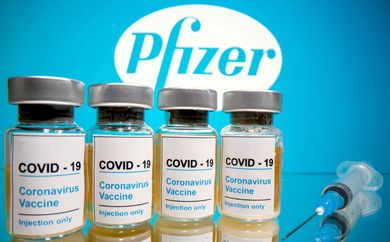 FILE PHOTO: Vials with a sticker reading, "COVID-19 / Coronavirus vaccine / Injection only" and a medical syringe are seen in front of a displayed Pfizer logo in this illustration taken October 31, 2020. REUTERS/Dado Ruvic